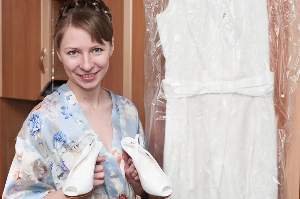 Mujer con zapatos blancos en las manos y vestido de novia en los hombros —  Fotos de Stock
