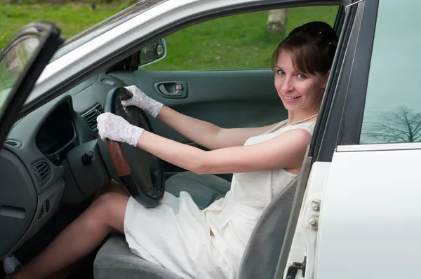 Frau in weißem Kleid und weißem Handschuh sitzt als Fahrerin im Auto. — Stockfoto