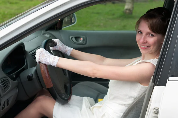 在白色的礼服和白手套坐在车里作为一个驱动程序中的女人. — 图库照片
