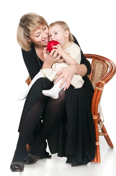 Średnim wieku kobieta jedzenie czerwone jabłko z małego dziecka wnuczka — Zdjęcie stockowe