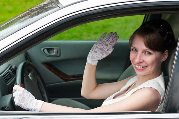 Mulher de vestido branco e luva branca sentada no carro como motorista — Fotografia de Stock