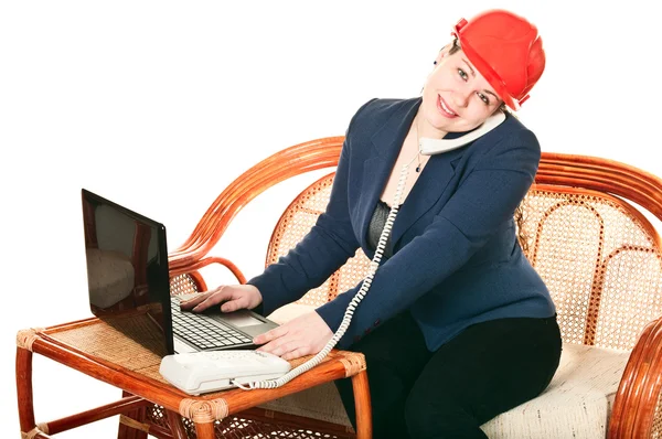 A piros sisakos lány a laptoppal leül az asztalhoz és pho-val telefonál. — Stock Fotó