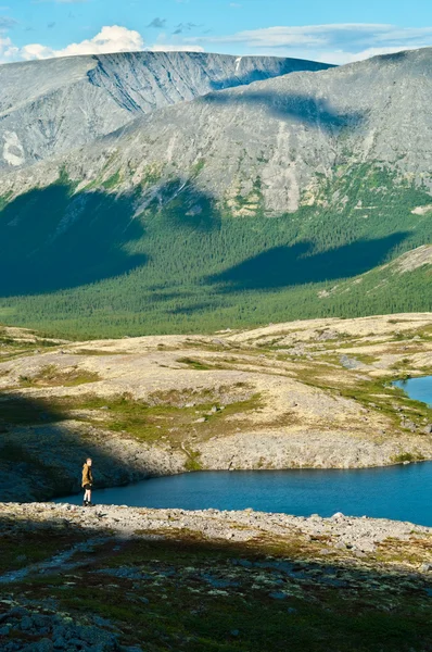 Man in mountain standing near lake and looking at camera from far away — Stock Photo, Image