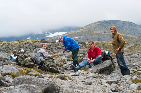 Groep reizigers in bergen met knapsacks rusten — Stockfoto
