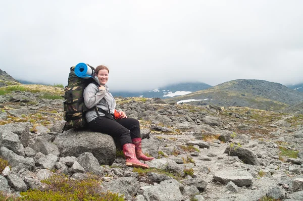 Backpacker een jonge vrouw zitten op rots in Bergen — Stockfoto