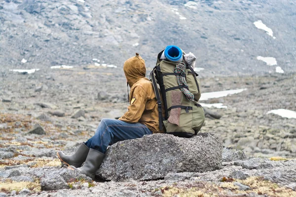 Backpacker ein älterer Mann sitzt auf einem Felsen in den Bergen — Stockfoto