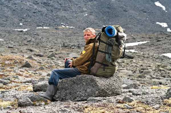 Backpacker starszy człowiek siedzi na skale w górach — Zdjęcie stockowe