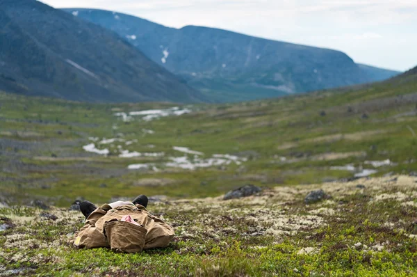 Homem descansando na grama nas montanhas — Fotografia de Stock