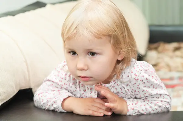 Kleines Kind, ein langweiliges Mädchen, das auf dem Sofa sitzt — Stockfoto
