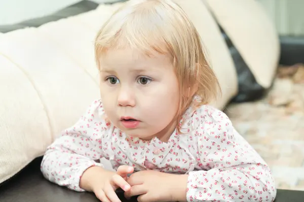 Małe dziecko dziewczyna dlond siedzi na kanapie i patrząc przez — Zdjęcie stockowe