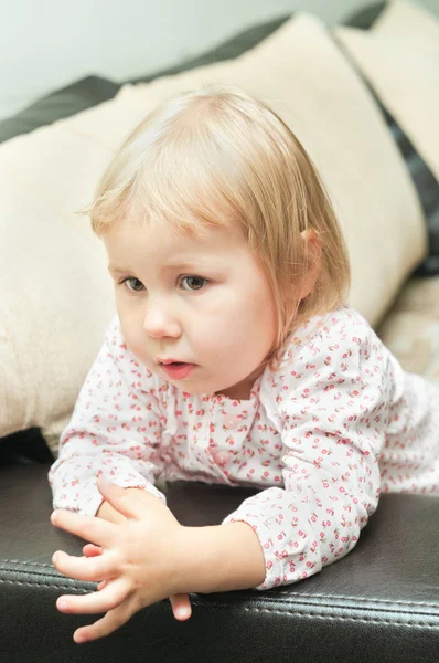 Criança uma menina dlond sentado no sofá e olhando através — Fotografia de Stock
