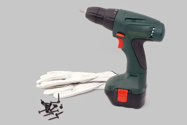 Elektromos screwdriwer eszköz, kesztyű és csavarokkal elszigetelt szürke backgro — Stock Fotó