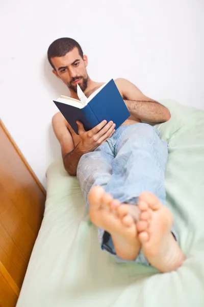Homme lisant un livre sur le lit — Photo