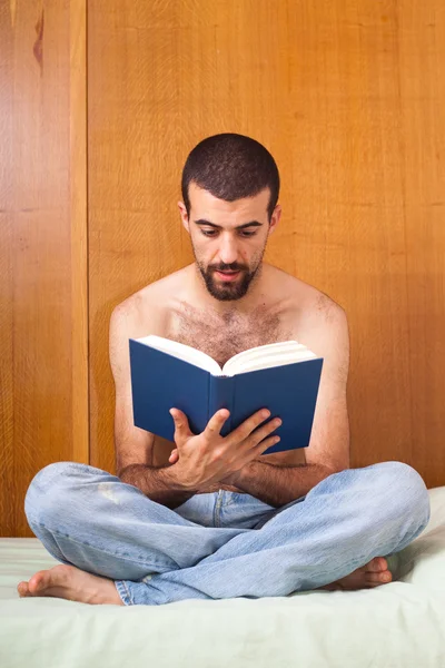 Mann liest ein Buch auf dem Bett — Stockfoto