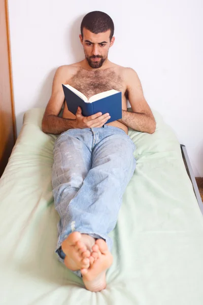 Muž s knihou na postel — Stock fotografie