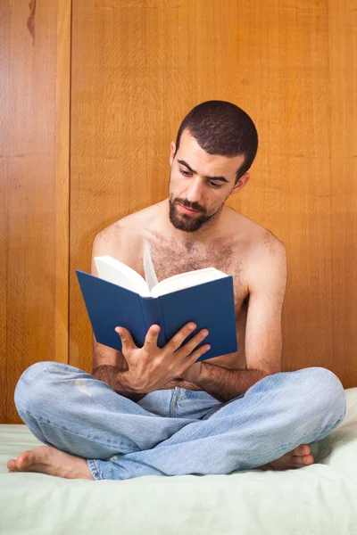 Człowiek czytając książkę na łóżku Obraz Stockowy