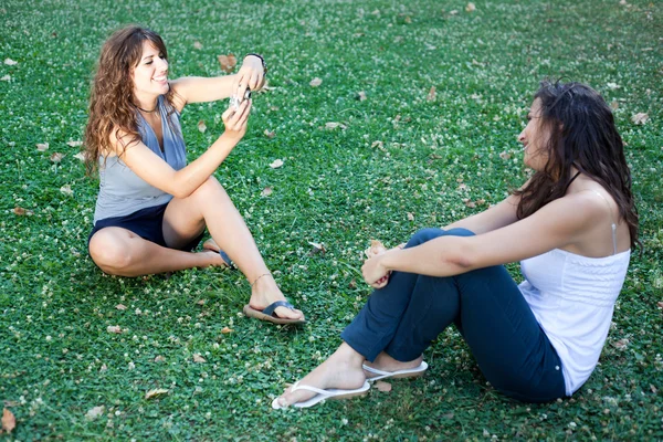 Девушка в парке делает фотографии своей подруге — стоковое фото