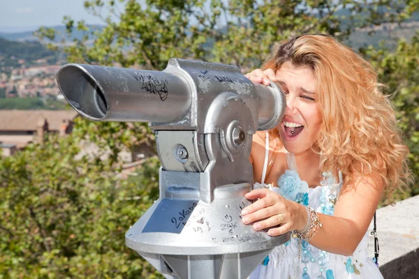 Sonriente chica rubia mirando a través del telescopio con la cara sorprendida —  Fotos de Stock