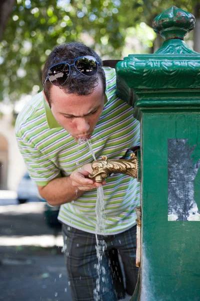 Muž pitné vody z veřejného fontána — Stock fotografie