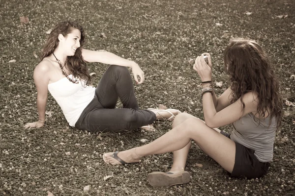 Tyttö puistossa ottaen kuvia hänen naispuolinen ystävä — kuvapankkivalokuva