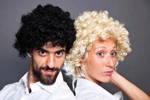 Mladý muž a žena s barevné legrační paruky — Stock fotografie