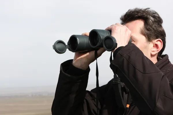 Muž se ohlíží přes dalekohled — Stock fotografie