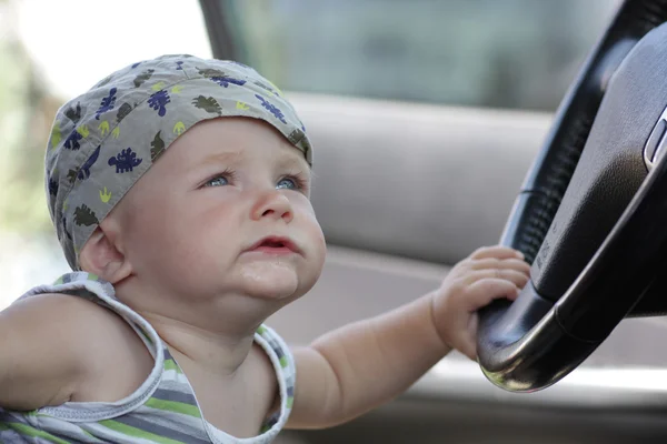 Забавный малыш держит колесо в машине — стоковое фото