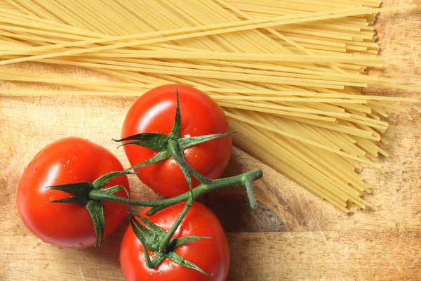 Сырые спагетти и помидоры — стоковое фото