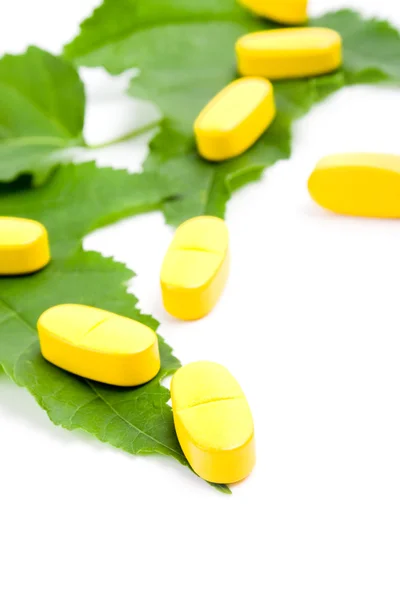 Vitamine pillen over groene bladeren — Stockfoto