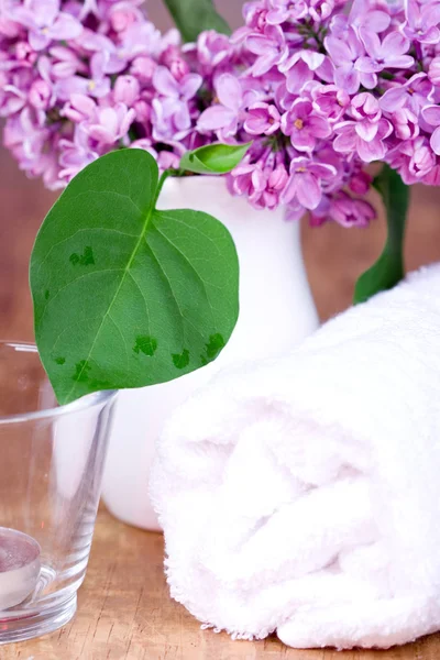 Rolled towel, lilac and candle — Stock Photo, Image