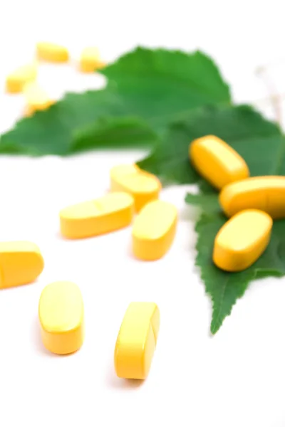 Vitamin hapları üzerinde yeşil yaprakları — Stok fotoğraf