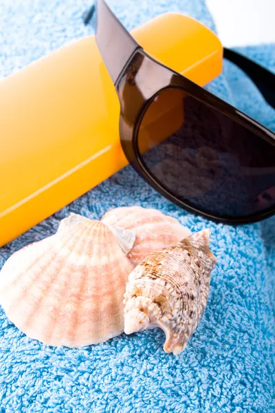 Toalla, conchas, gafas de sol y loción — Foto de Stock
