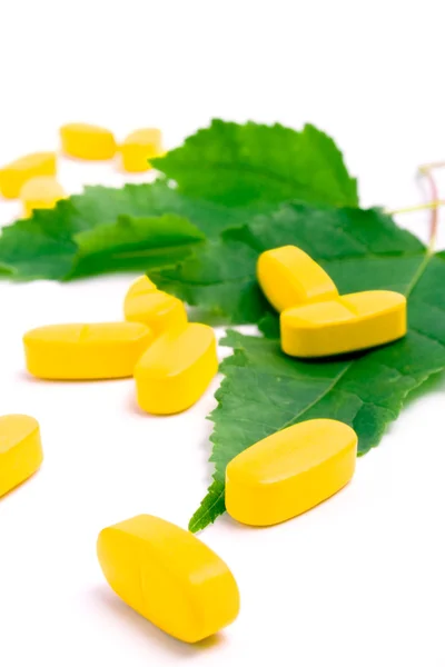 Vitamin pills over green leaves — Stock Photo, Image