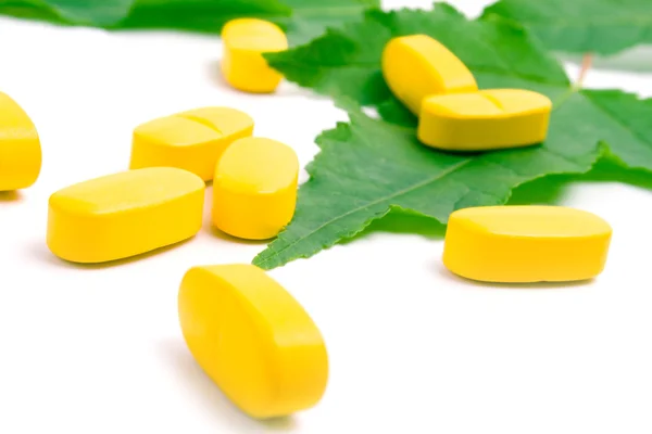 Yellow vitamin pills over green leave — Stock Photo, Image