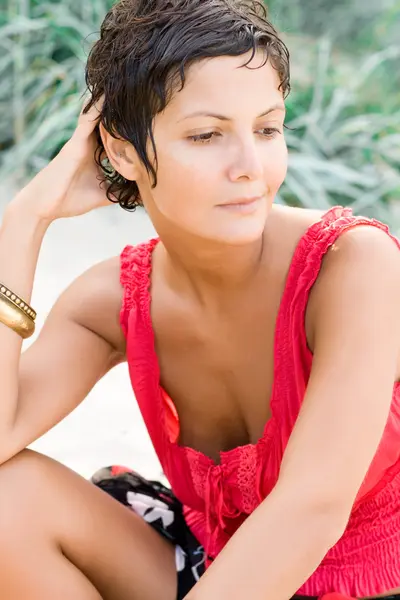 Женщина в красном сидит на песке — стоковое фото