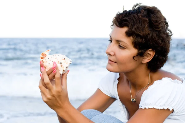 Frau am Meeresufer mit einer Herzmuschel — Stockfoto