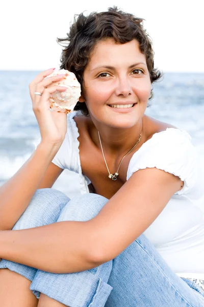Donna sulla costa con un cockleshell in mano — Foto Stock