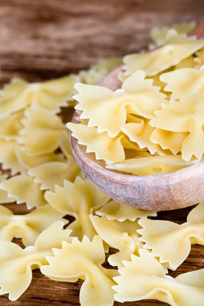 Uncooked pasta in wooden spoon — Stock Photo, Image