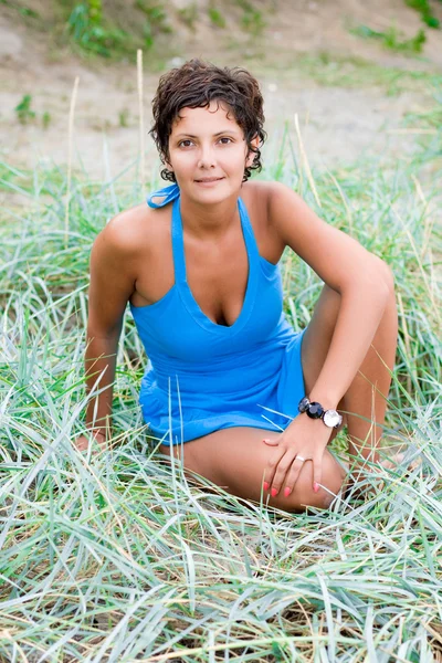 Женщина в синем сидит в траве — стоковое фото