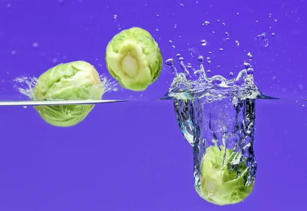 Brussels sprouts falling in water — Stock Photo, Image