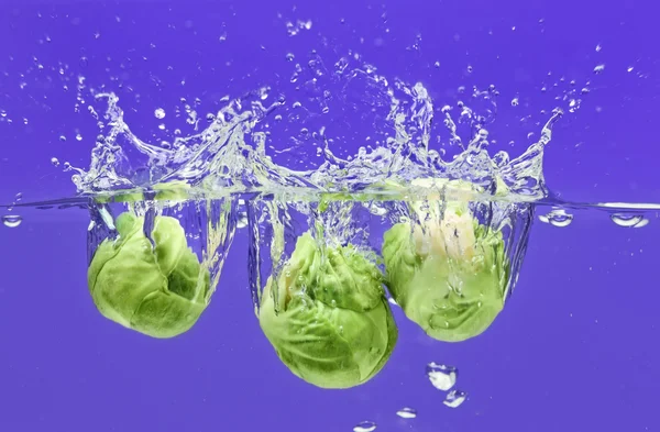 Brussels sprouts falling in water — Stock Photo, Image