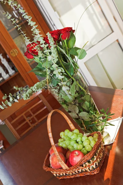 Složení s košíkem ovoce a květiny ve váze — Stock fotografie