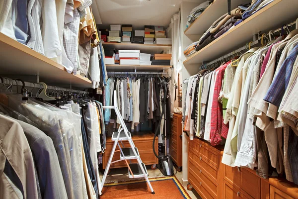 Roupeiro com muitas roupas e escada passo — Fotografia de Stock
