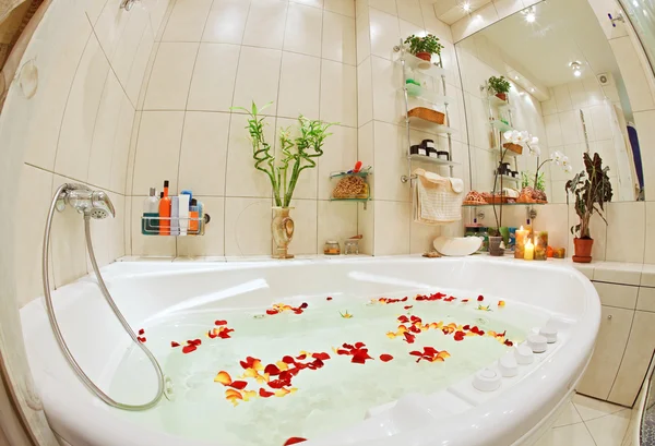 Cuarto de baño moderno en tonos cálidos con jacuzzi y pétalos de rosa amplia vista angular —  Fotos de Stock