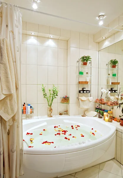 Современная ванная комната в теплых тонах с джакузи и лепестками роз широкий угол зрения — стоковое фото