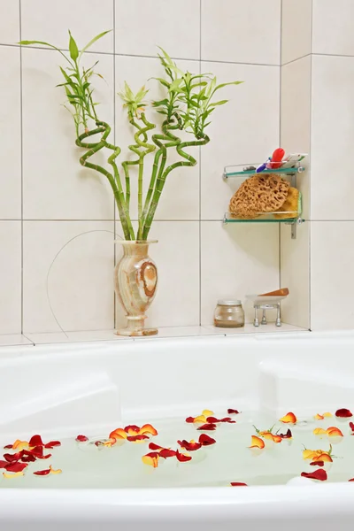 Parte do banheiro com pétalas de rosa flutuando na água — Fotografia de Stock