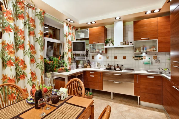 Interior da cozinha com móveis de madeira, mesa e muitos utensílios — Fotografia de Stock