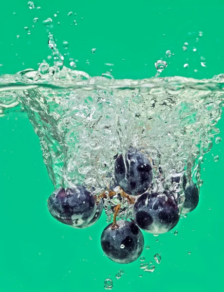 Um bando de uvas flutuando na água com bolhas de ar — Fotografia de Stock