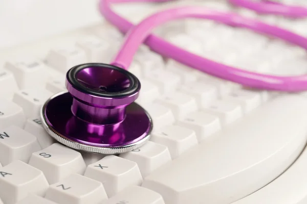 Pink stethoscope on white keyboard — Stock Photo, Image