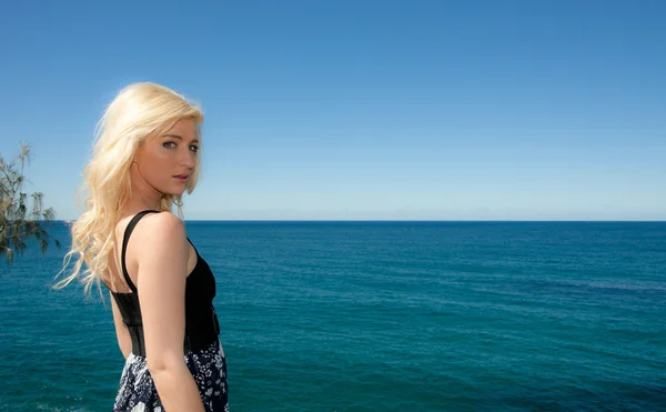 Jovem mulher olha sobre o oceano azul — Fotografia de Stock